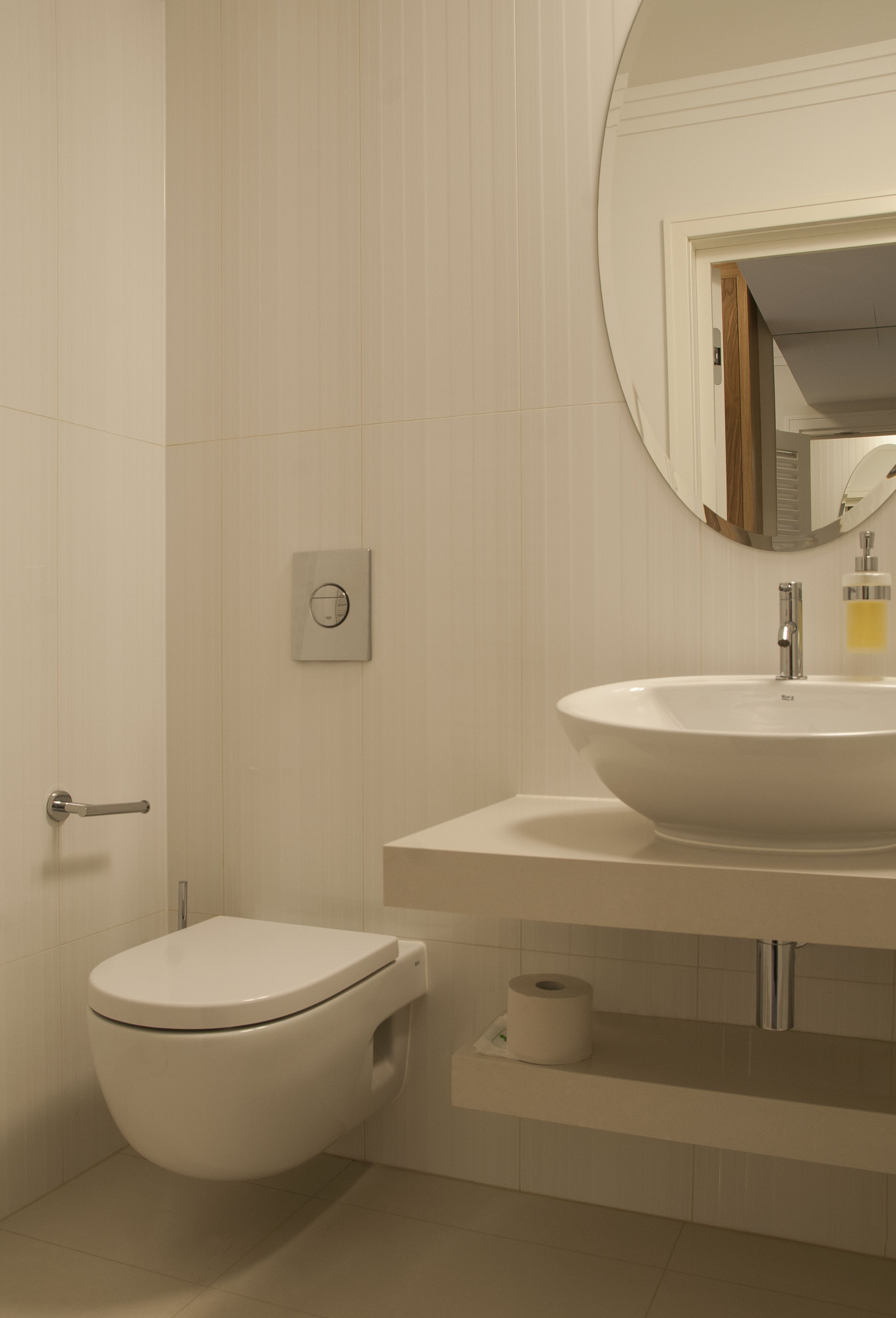 Un baño moderno con inodoro, lavamanos y espejo.