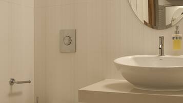 Un baño moderno con inodoro, lavamanos y espejo.