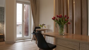 A modern living room with a wooden dining table, a black chair, and a vase of tulips. - Baltica Residence (Sopot)