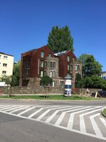A modern building with a stone facade and a large tree in front.