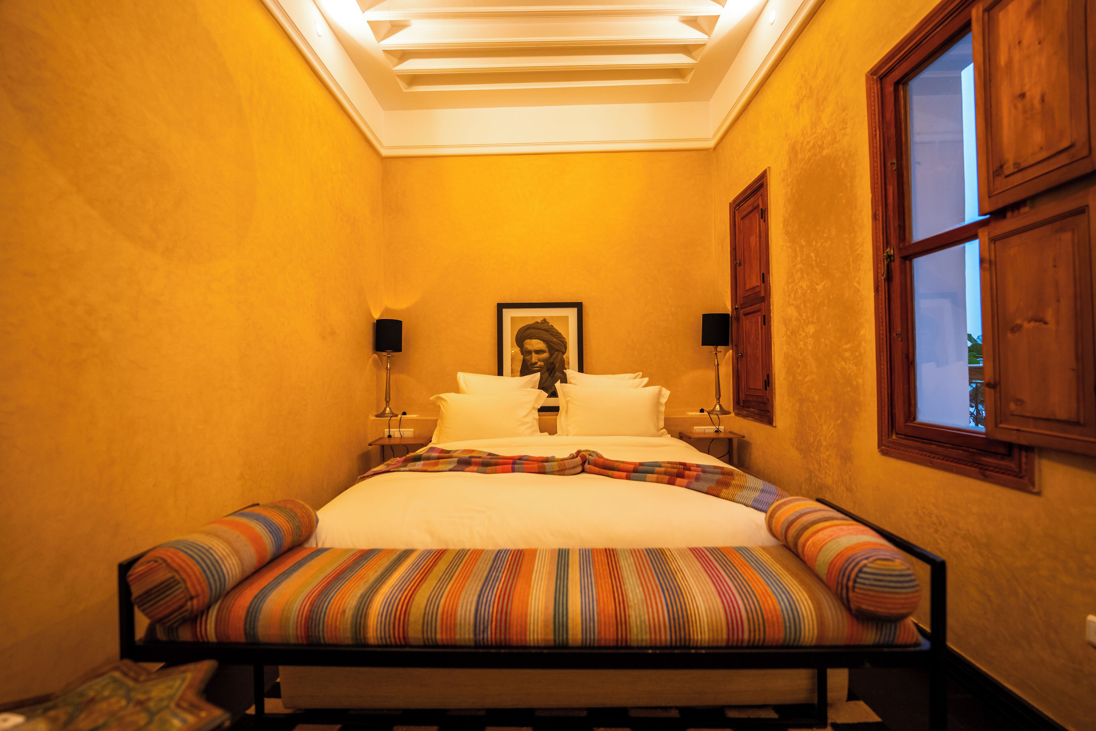 A bedroom with a bed, a framed picture on the wall, and two bedside lamps.