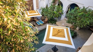 Un espace extérieur aménagé avec des parasols, des plantes en pot et un sol à motifs.