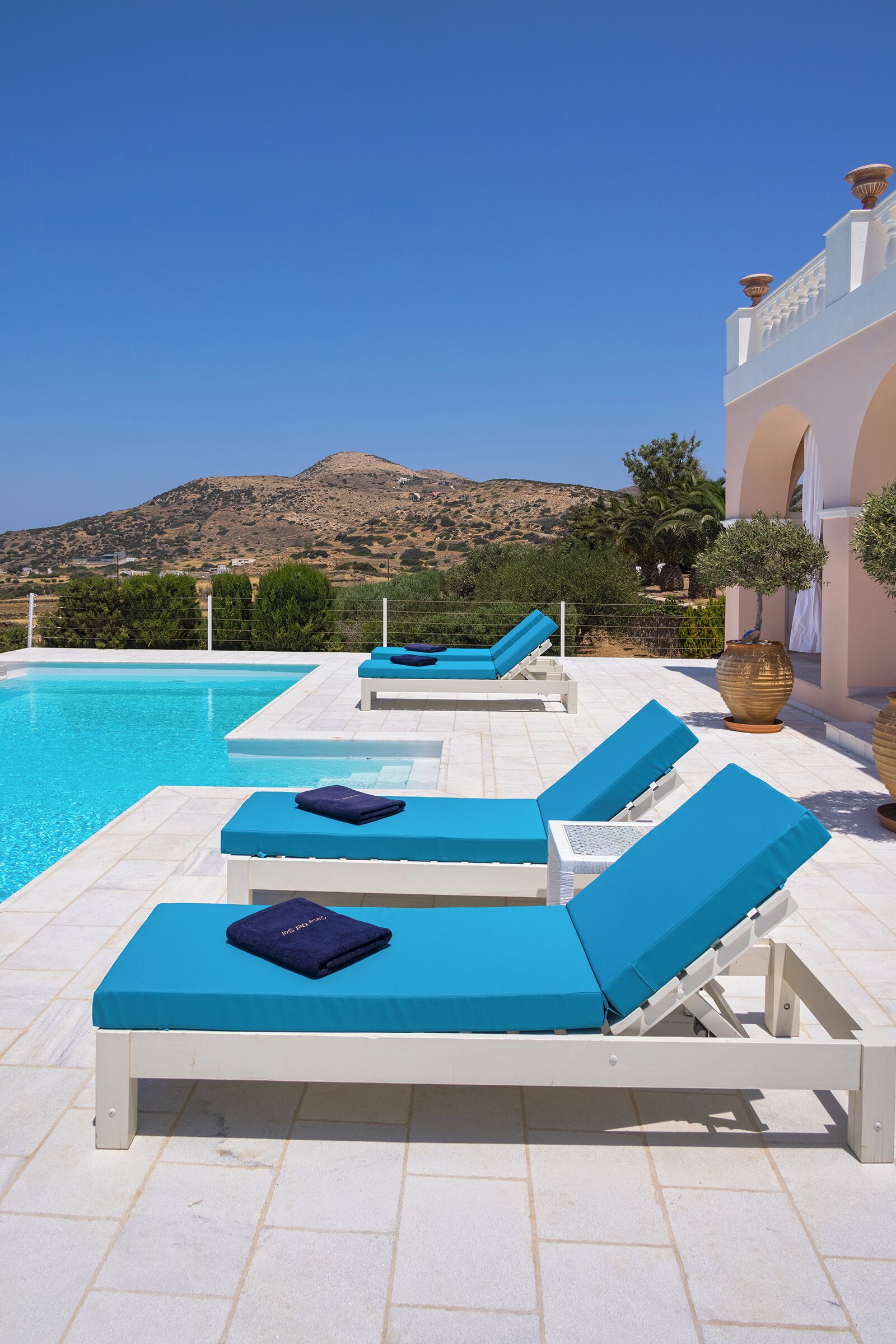 Zona de piscina con sillones de descanso y vistas a un paisaje montañoso.
