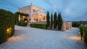 A two-story house with a gravel driveway, stone walls, and a well-maintained garden.