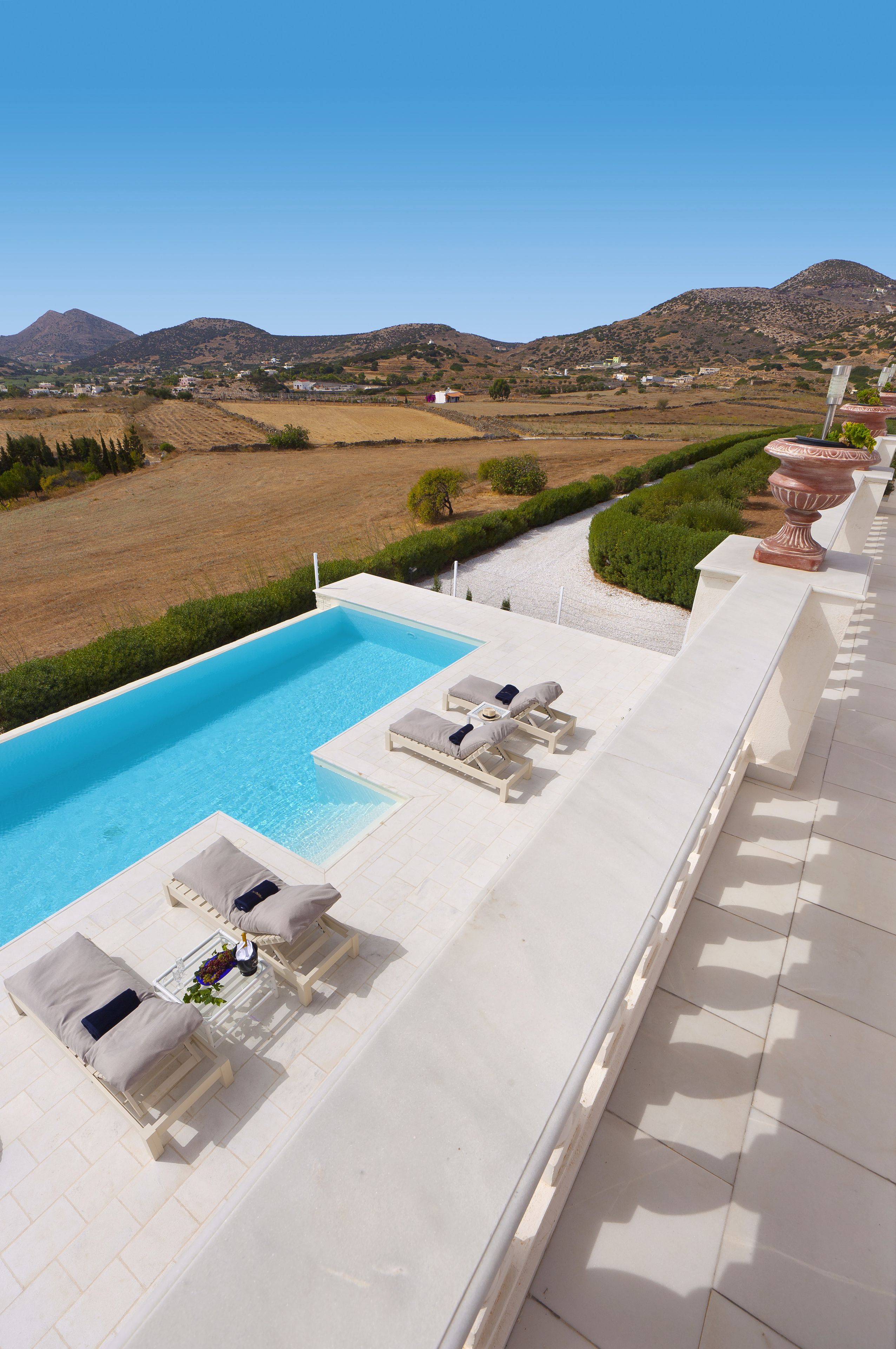 A poolside area with lounge chairs and a view of the countryside.
