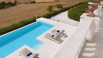 A poolside area with lounge chairs and a view of the countryside.