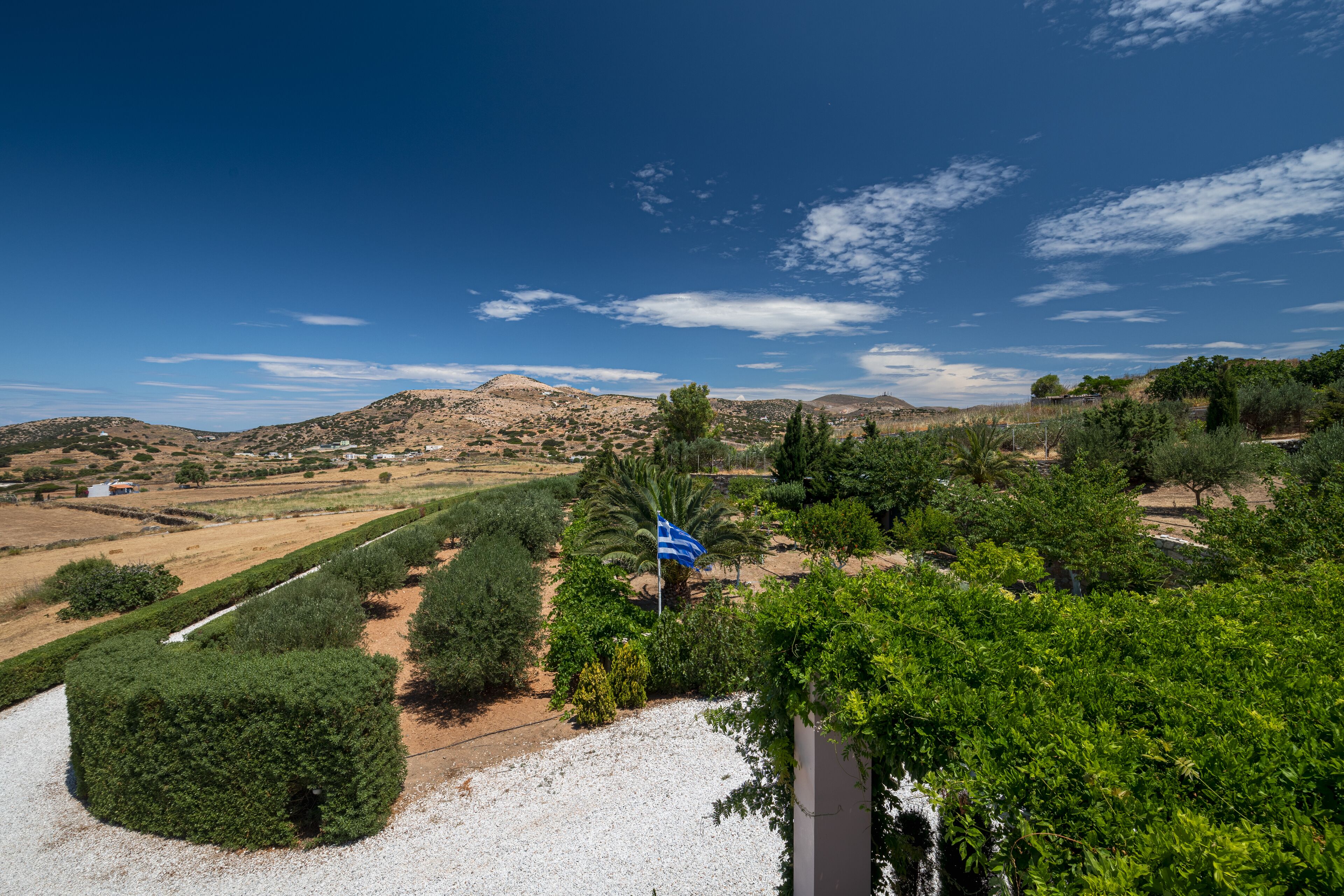 A rural landscape with a clear sky, rolling hills, and scattered trees.