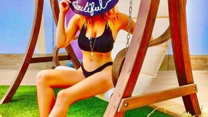 A person sitting on a swing with a large hat, wearing a bikini, in an outdoor setting with grass and a wooden swing set. - Wellness Suite Na Canunà (Roddi)