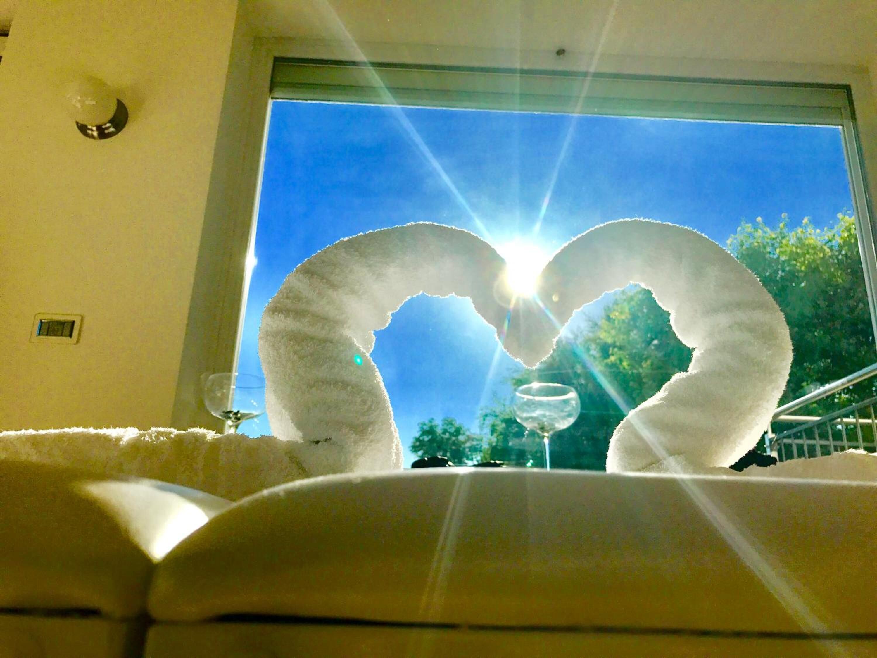 Una stanza con un'ampia finestra, un oggetto decorativo a forma di cuore bianco e vista sugli alberi.