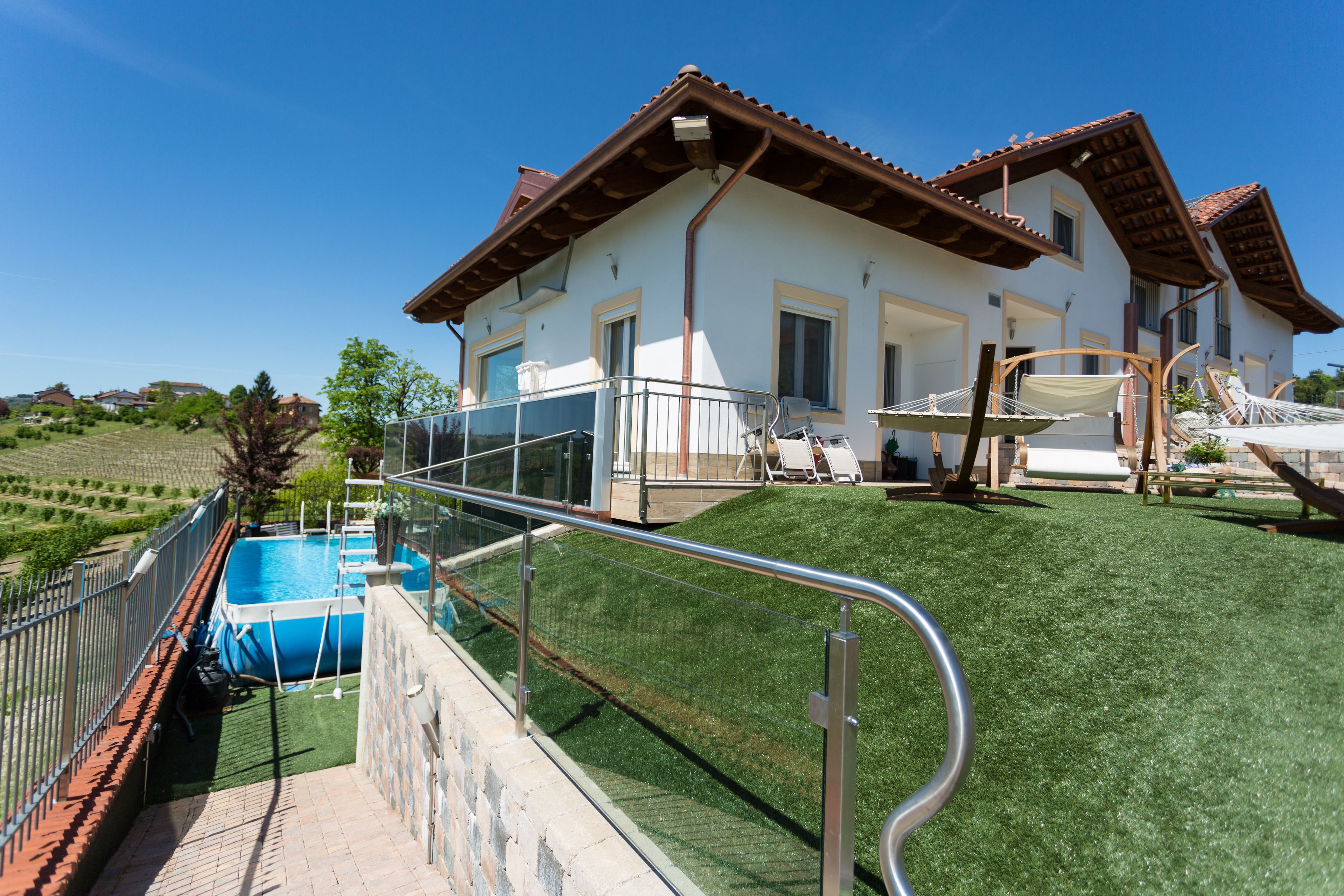 Ein Haus mit Swimmingpool, einer Rasenfläche und einem Balkon mit Geländer.