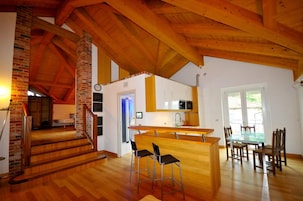 Una cocina amplia con una isla central, suelo de madera y una escalera que lleva a un nivel superior.