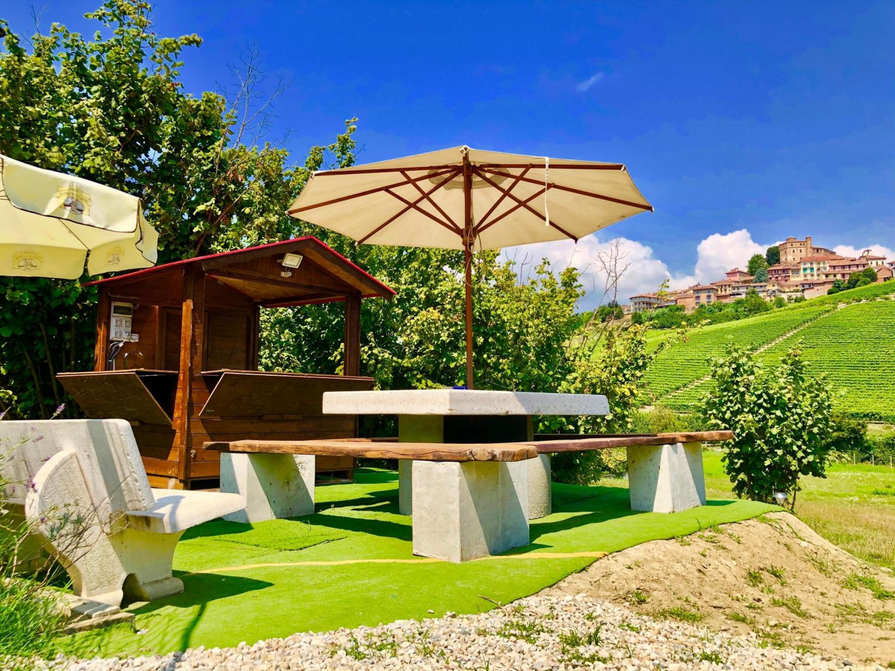 A rustic outdoor seating area with a wooden structure, a table, and a large umbrella.