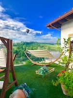 Un patio trasero con una hamaca, una mesa con flores y vistas al campo con globos aerostáticos.
