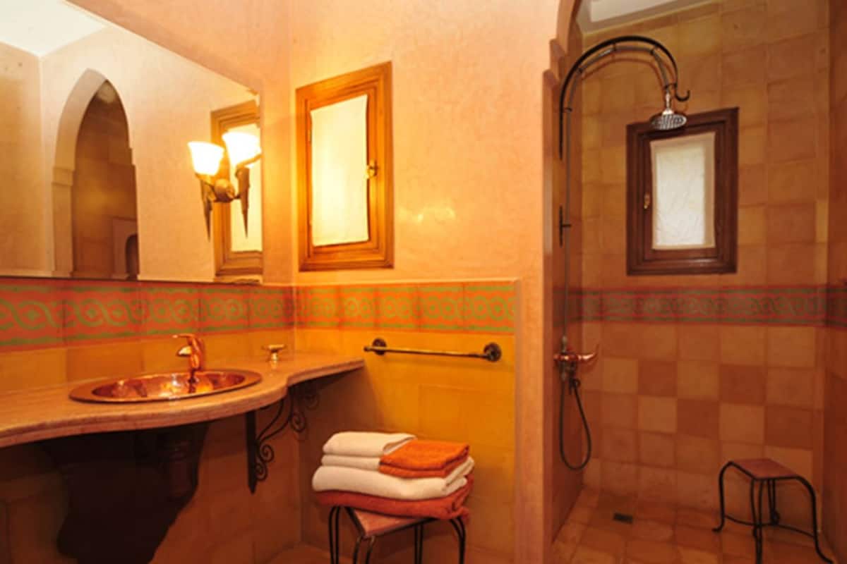 A bathroom with a sink, mirror, towel rack, and shower.