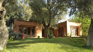 A two-story house with a front porch, surrounded by trees and a well-maintained lawn. - MAROC LODGE Atlas Mountain Retreat  (Amizmiz)