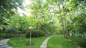 A stone pathway leading through a lush garden with various trees and shrubs. - MAROC LODGE Atlas Mountain Retreat  (Amizmiz)