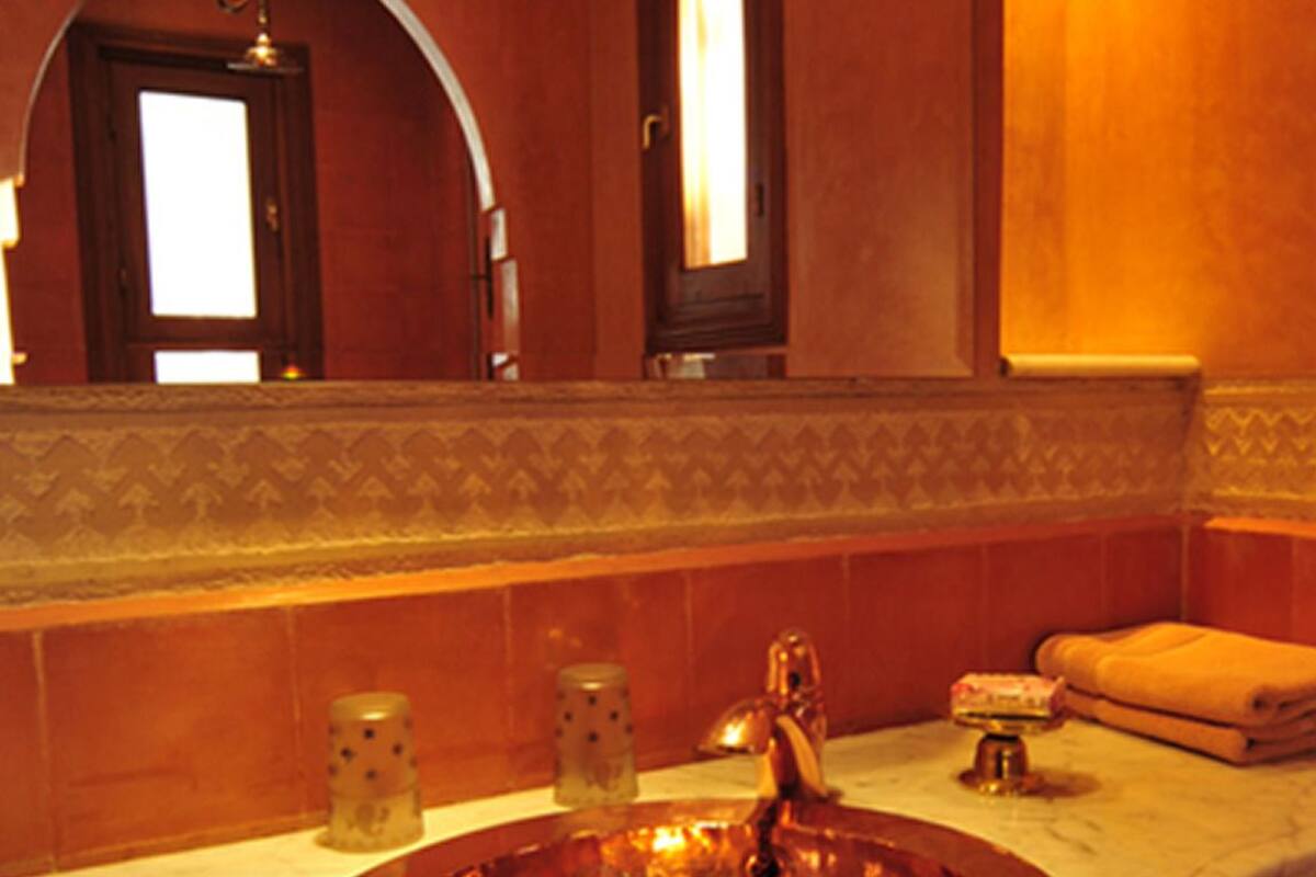A bathroom with a copper sink, a mirror, and a towel on the counter.