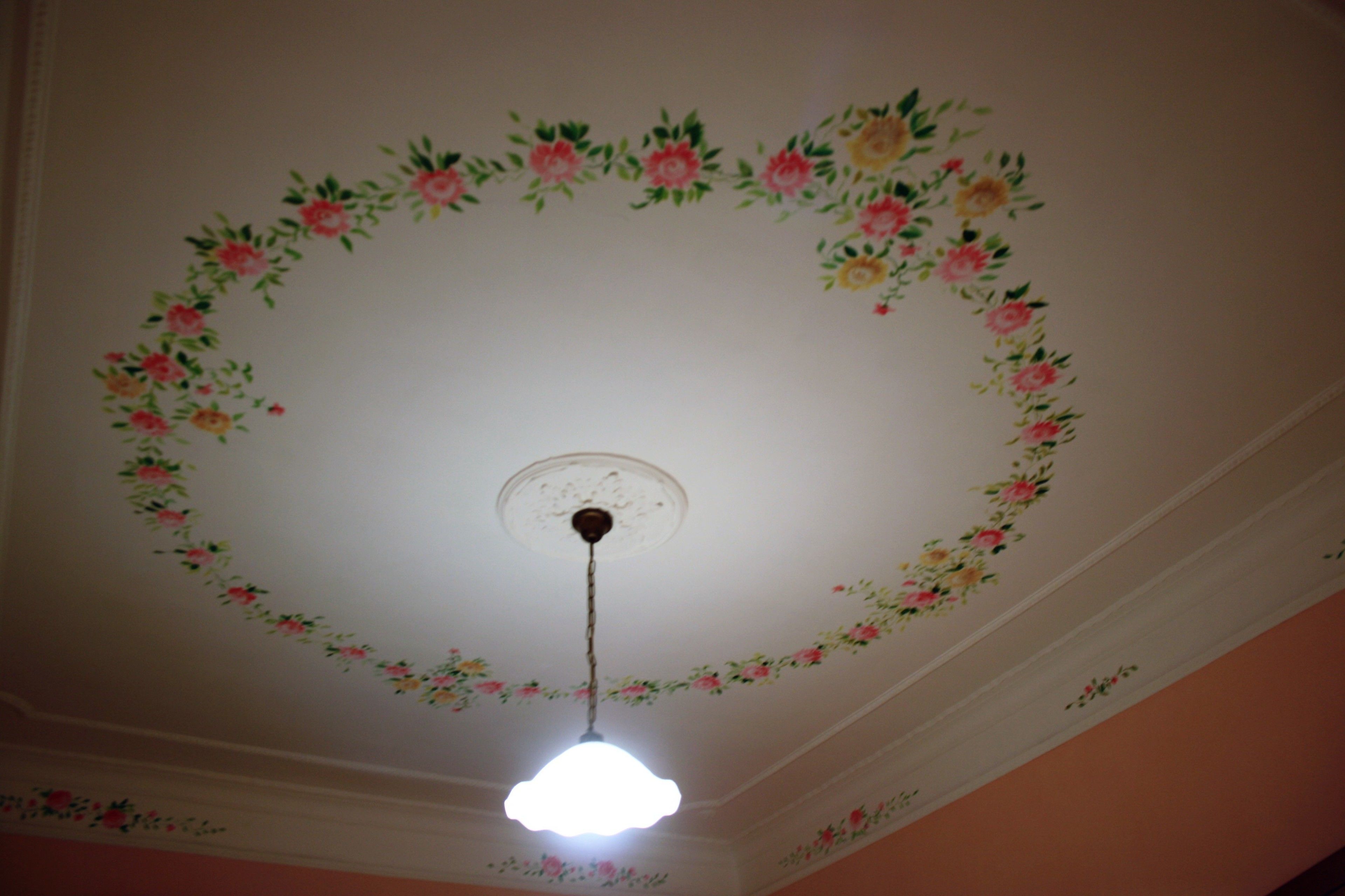 A ceiling with floral patterns and a hanging light fixture.