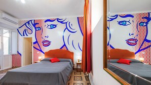 A room with two beds, a mirror, and a wall with a pop art design. - Affittacamere Al Seminario (Tivoli)