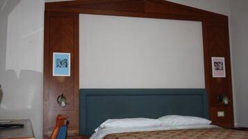 Een hotelkamer met een groot bed, een houten hoofdbord en twee ingelijste foto's aan de muur.