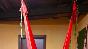 A hammock suspended from the ceiling in a room with a wooden door and a framed picture on the wall. - Affittacamere Al Seminario (Tivoli)