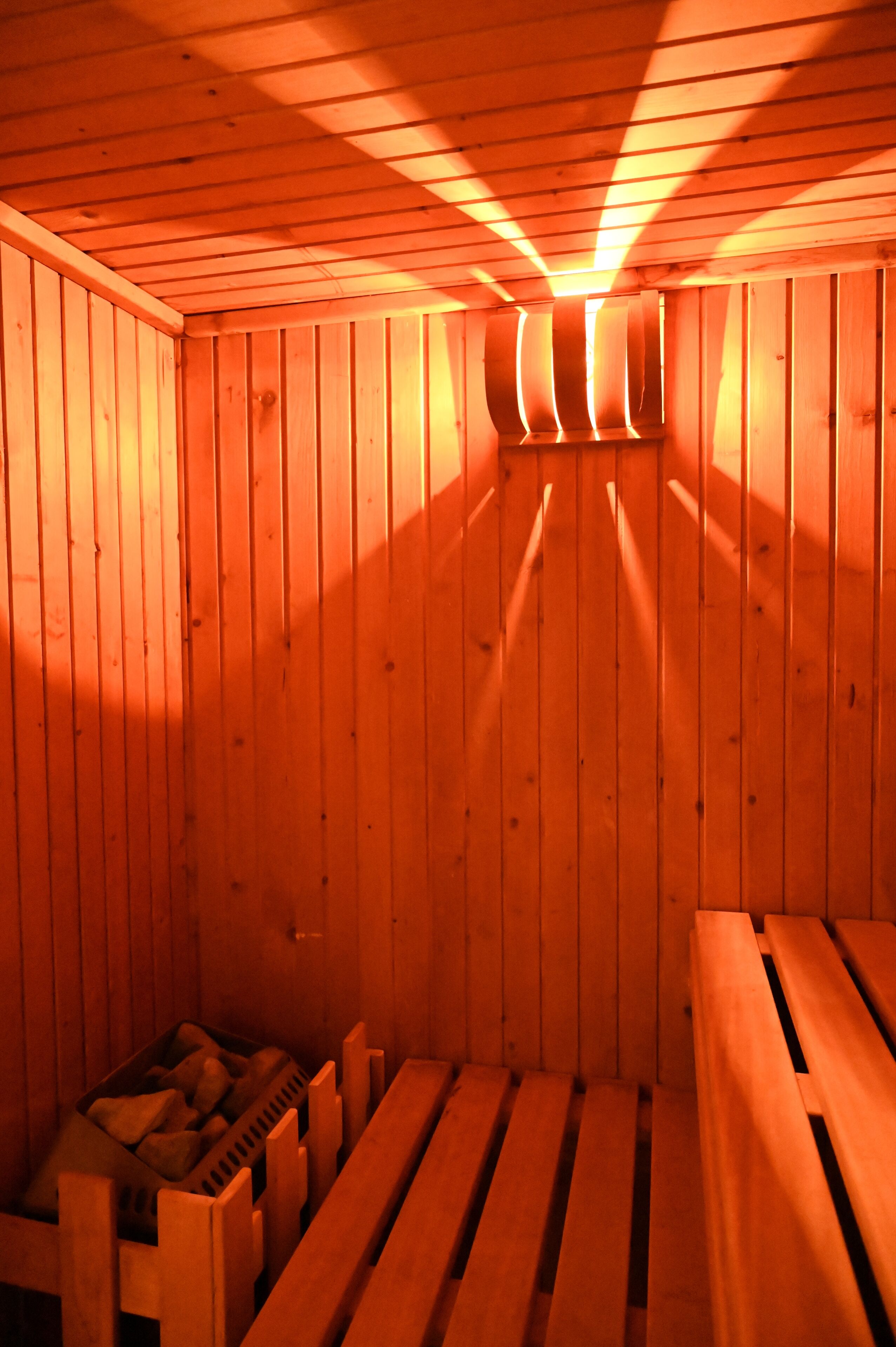 A sauna room with wooden benches and a bench with a backrest.
