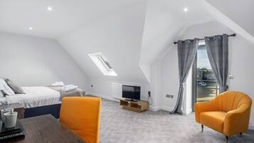 A modern, well-lit room with a bed, a TV, and a dining table.