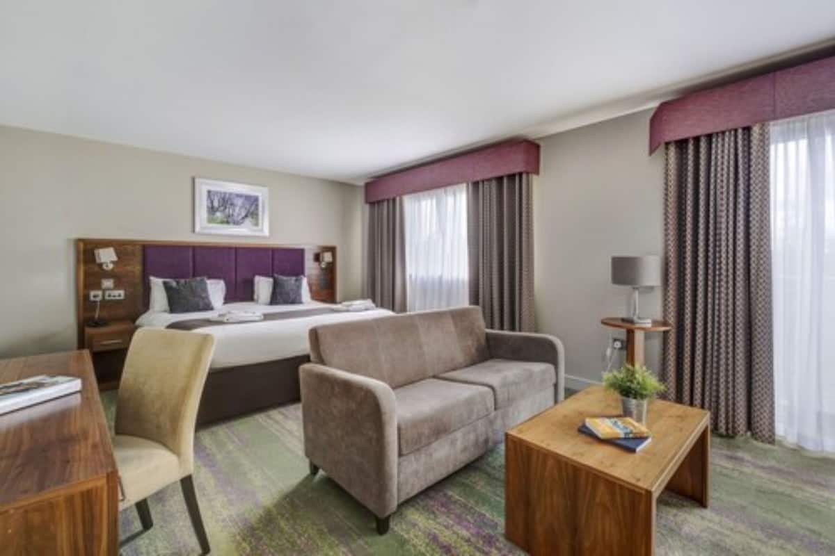 Une chambre d’hôtel avec un lit, un canapé, un bureau et une chaise.