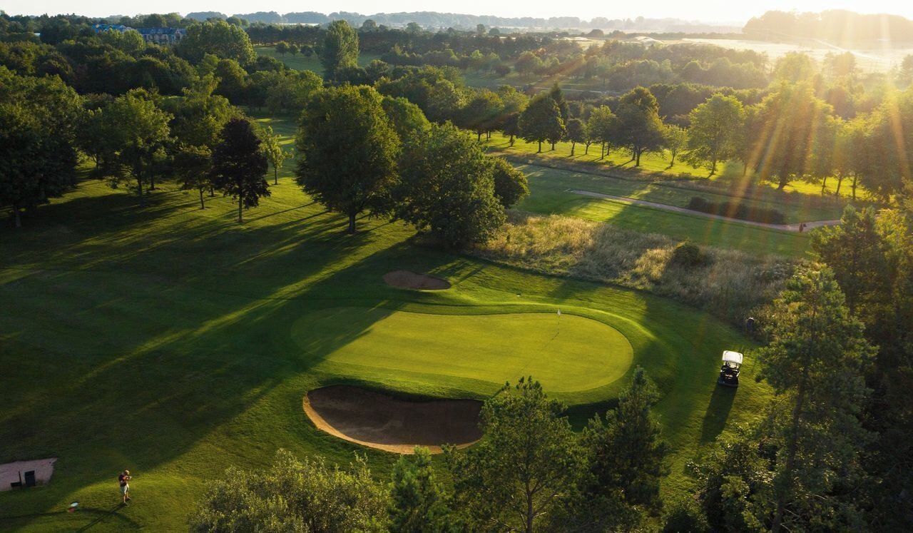 A golf course with a well-maintained fairway, sand bunkers, and trees.