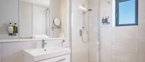 A modern bathroom with a glass shower enclosure, a white sink, and a large mirror.