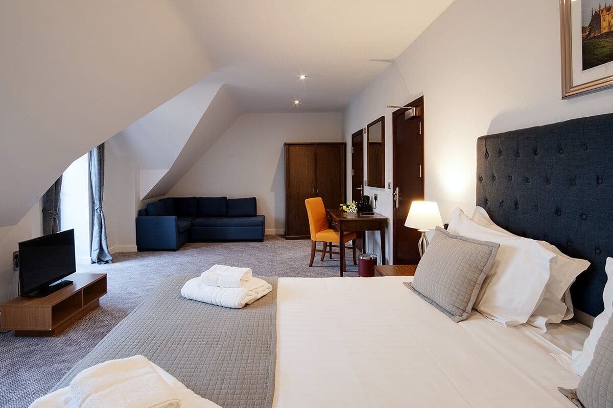 Une chambre d’hôtel avec un grand lit, une télévision, un canapé et un bureau avec une chaise.