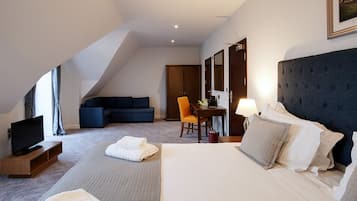 Una habitación de hotel con una cama grande, televisión, sofá y escritorio con silla.