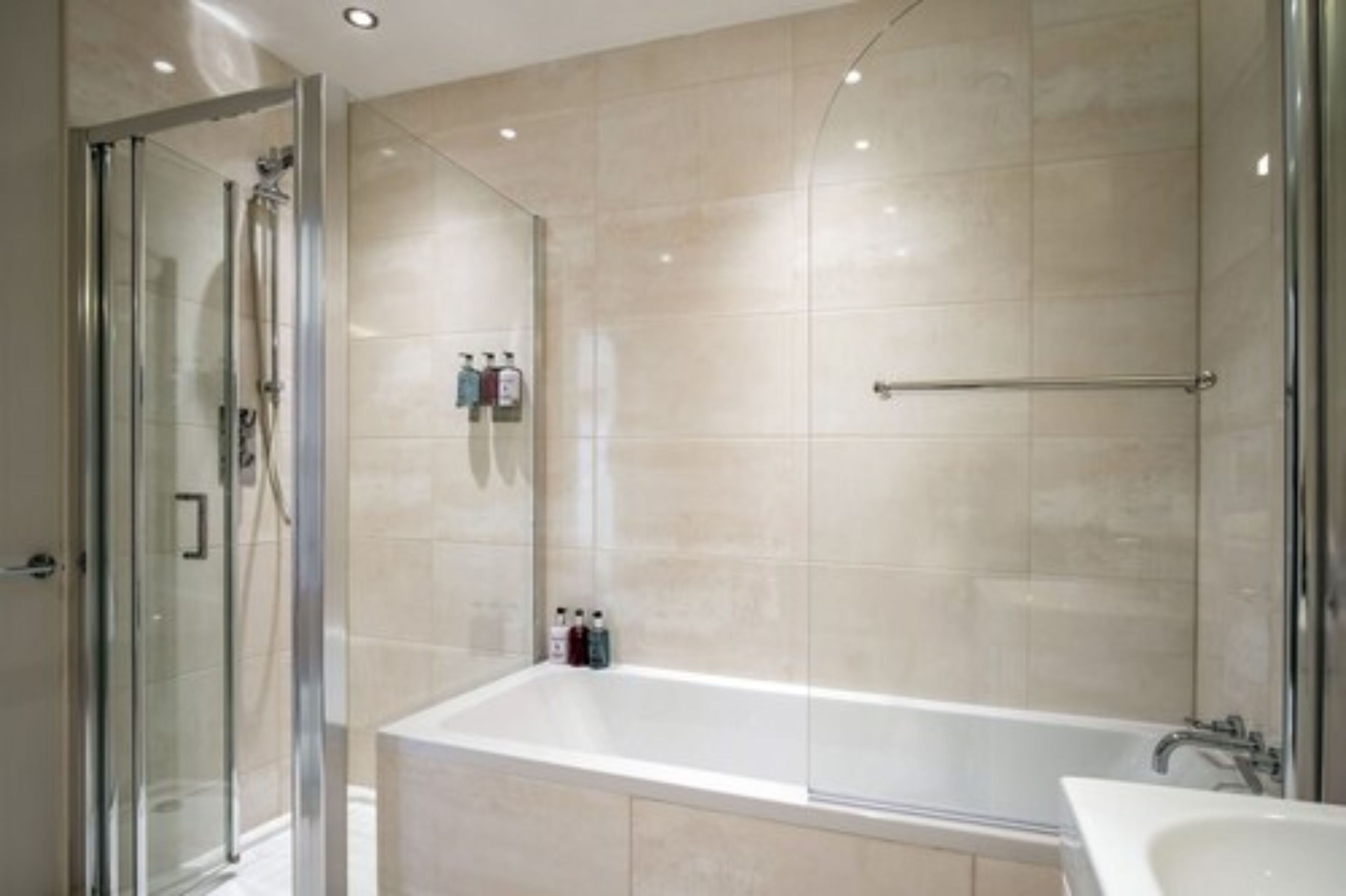 A modern bathroom with a glass-enclosed shower, a freestanding bathtub, and a sink.