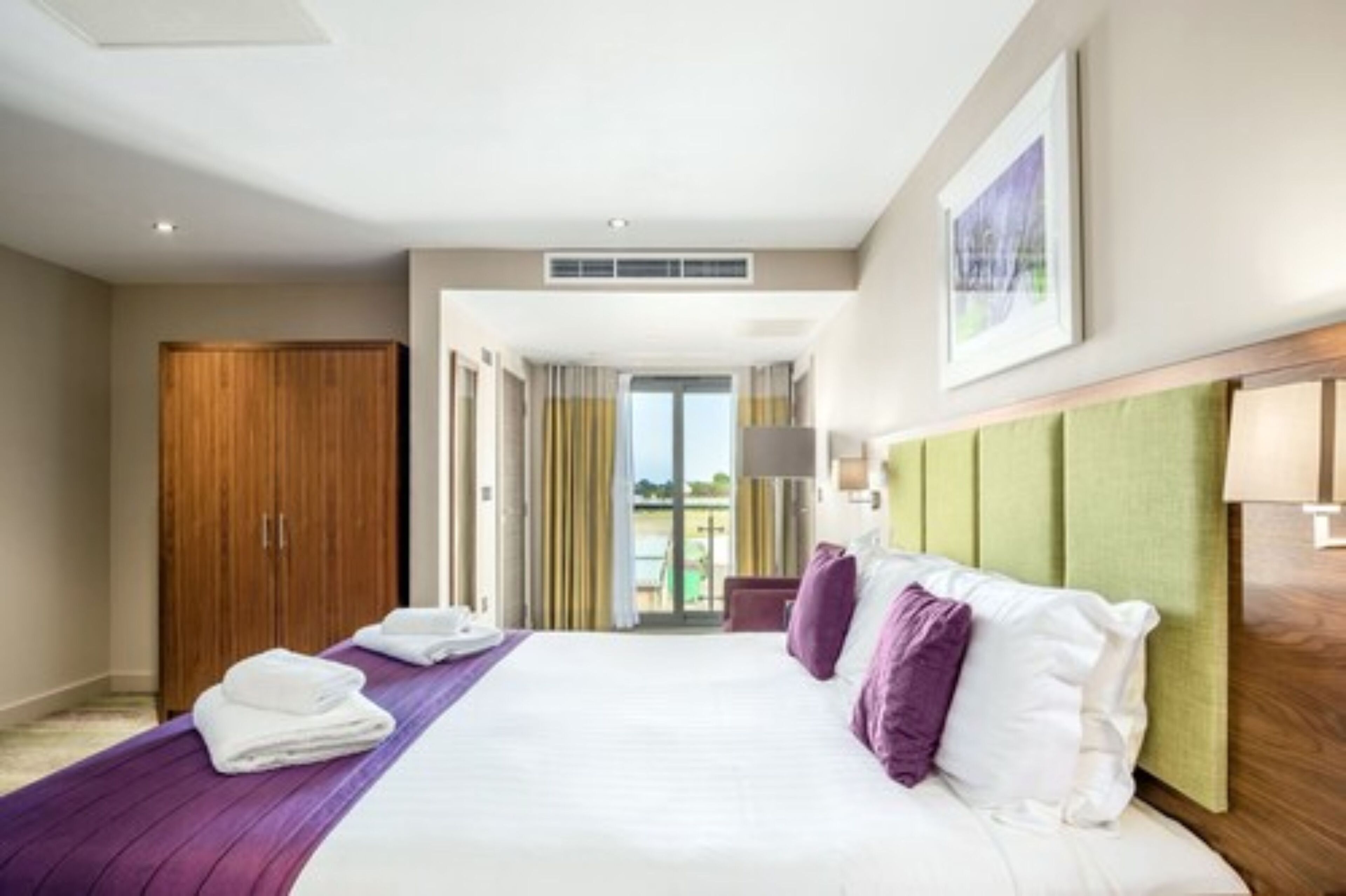 Habitación de hotel con una cama grande, un armario y vistas al exterior.