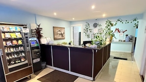 A reception area with a counter, a vending machine, and a wall-mounted clock. - Melville Country Inn (Melville)