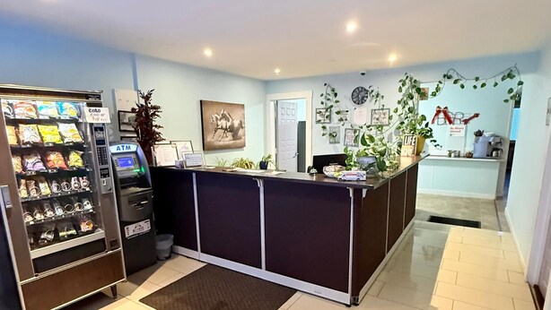A reception area with a counter, a vending machine, and a wall-mounted clock. - Melville Country Inn (Melville)