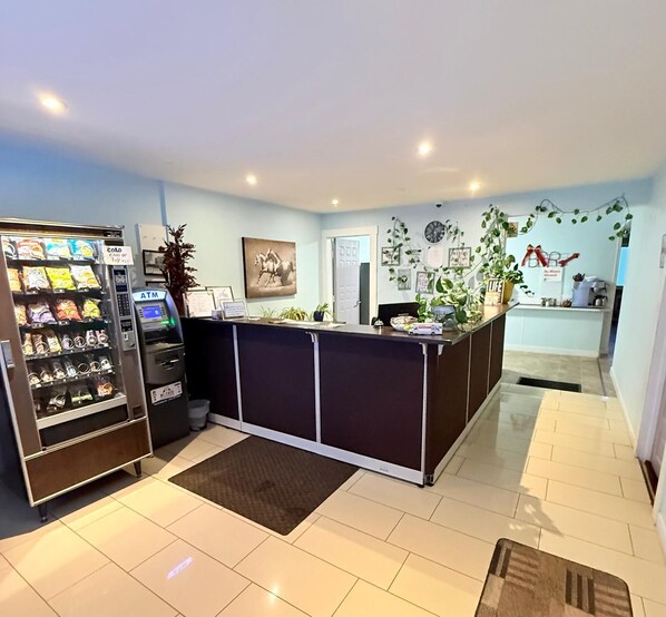 A reception area with a counter, a vending machine, and a wall-mounted clock. - Melville Country Inn (Melville)