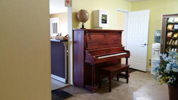A piano in a room with a door, a water dispenser, and a plant.