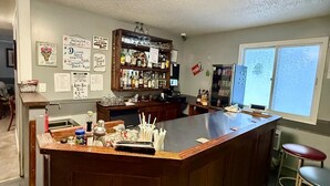 A kitchen with a bar area, wooden cabinets, and a large island with stools. - Melville Country Inn (Melville)