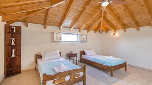 Een slaapkamer met twee houten bedden, een houten wandplank en een schuin plafond met zichtbare balken.