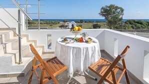 Een balkon met een ronde tafel voor twee personen, met uitzicht op een schilderachtig zeegezicht.