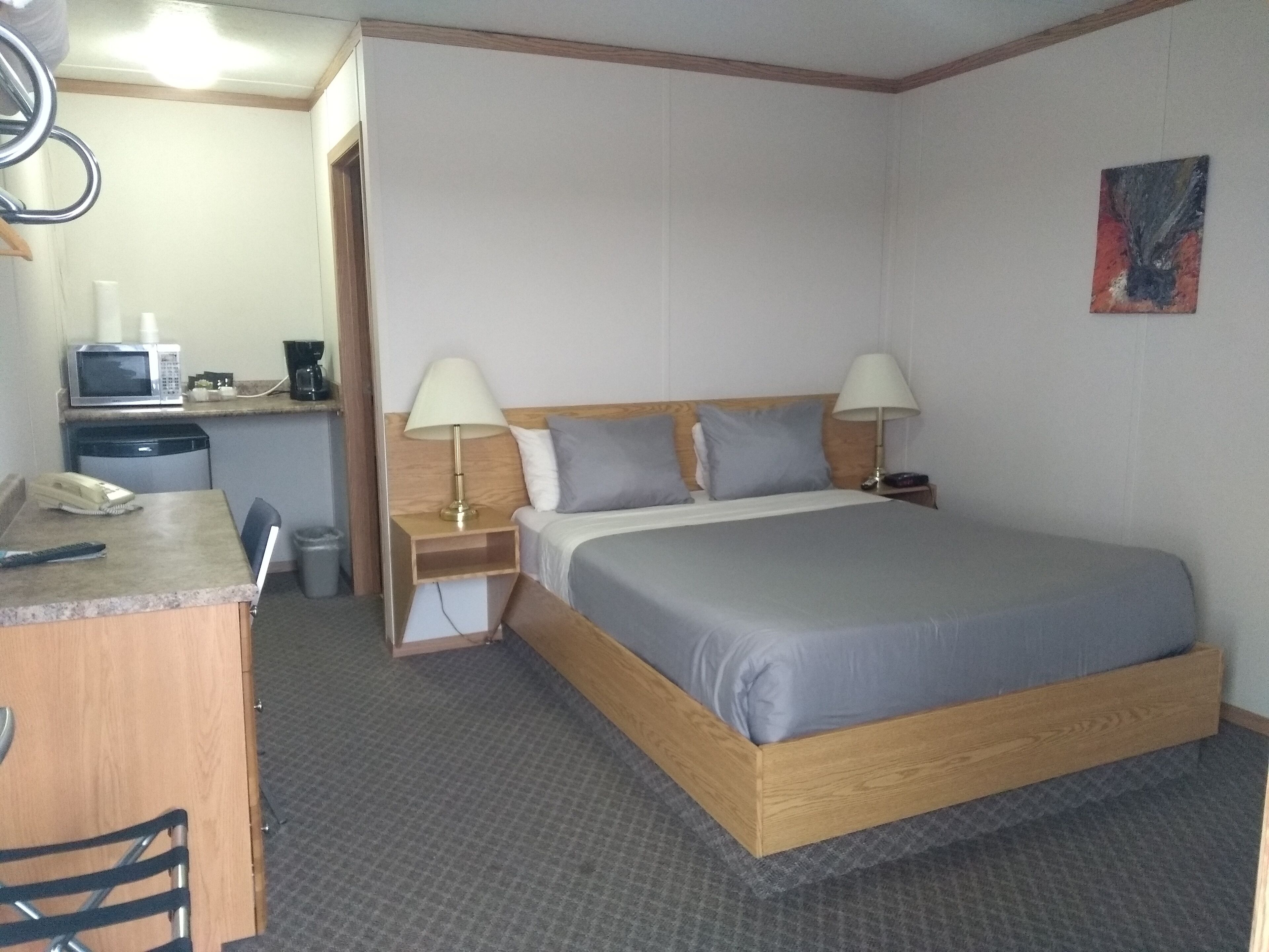 Een hotelkamer met een bed, nachtkastjes, een bureau, een magnetron en een stoel.