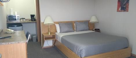 Een hotelkamer met een bed, nachtkastjes, een bureau, een magnetron en een stoel.