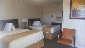 A hotel room with two beds, a chair, a nightstand with a lamp, a wall-mounted air conditioner, and a 'no smoking' sign. - Sundown Motel (Watrous)