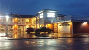 A motel with a 'NOW OPEN' sign, a 'FREE BREAKFAST' sign, and a 'WILDCATS MOTEL' sign. There are two cars parked in front. - Super 8 by Wyndham Watrous (Watrous)