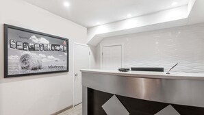 A reception area with a modern design, featuring a reception desk, a framed welcome sign, and a door. - Super 8 by Wyndham Watrous (Watrous)