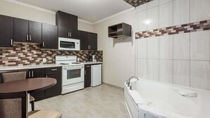 A modern kitchen with dark cabinets, a white microwave, and a tiled backsplash. - Super 8 by Wyndham Watrous (Watrous)