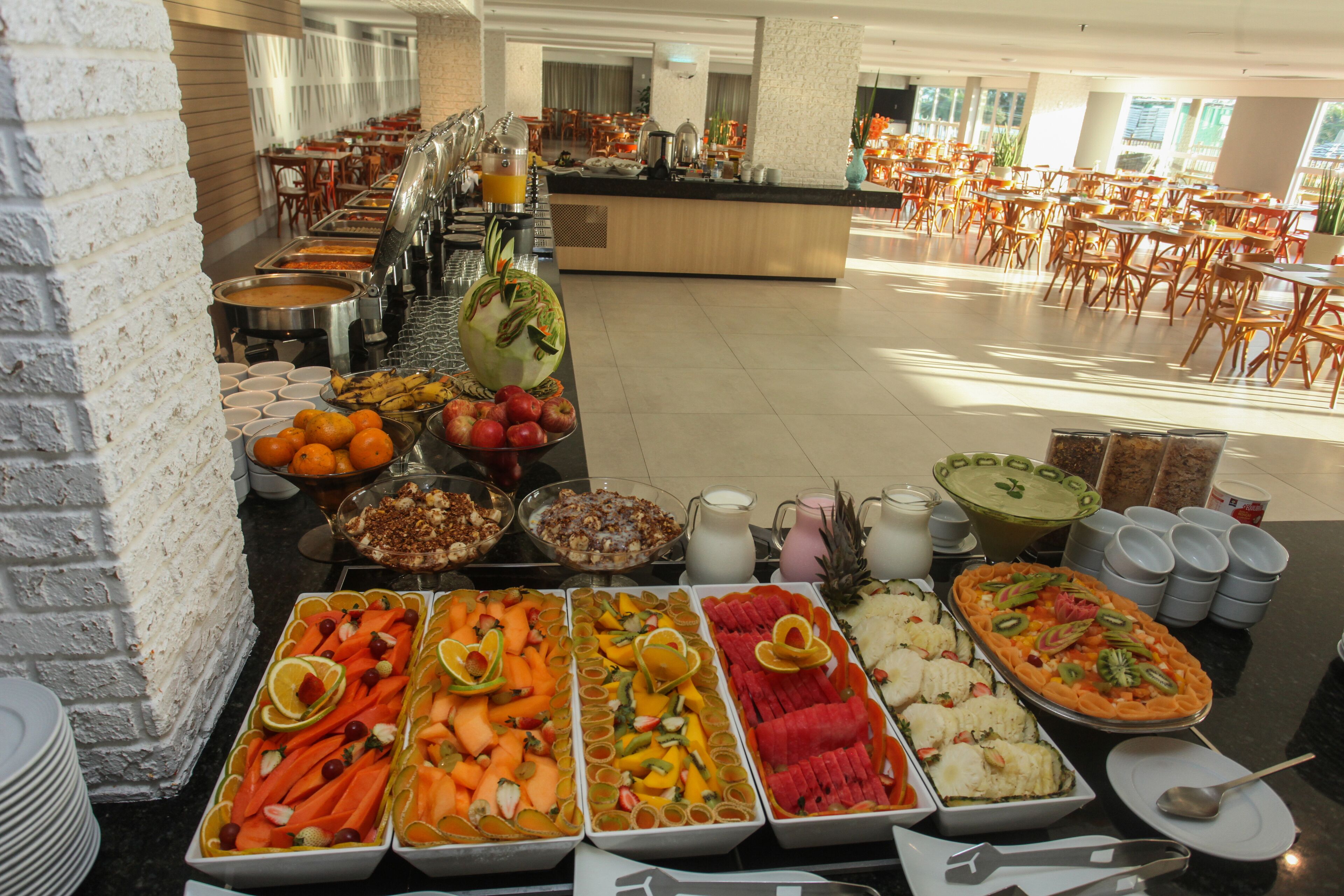 A buffet with various food items and a seating area with tables and chairs.