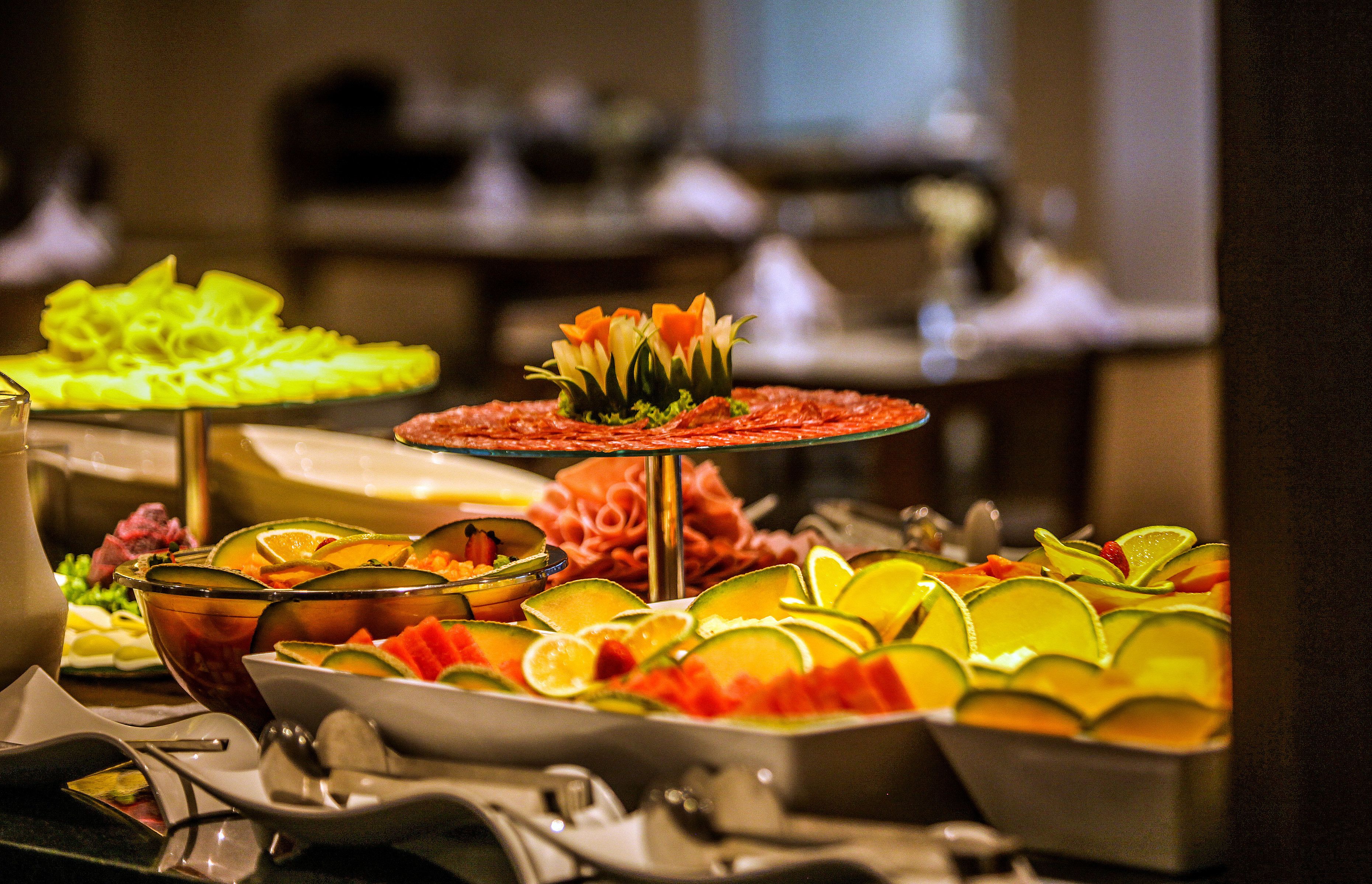 A buffet with various fruit and vegetable dishes, including melon and carrot slices.
