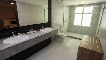 A modern bathroom with two sinks, a large mirror, a glass shower enclosure, and a wooden vanity.